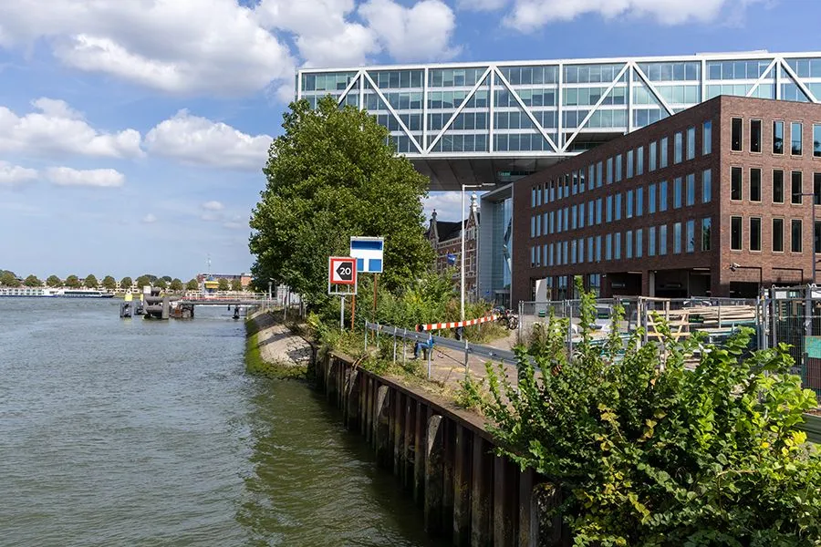 Uitzicht op de Nassaukade in Rotterdam met water, kade en moderne bebouwing; gebied wordt heringericht voor aansluiting op nieuwbouwproject Hefkwartier.