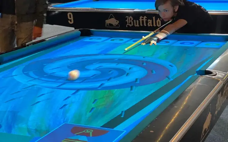 Twee spelers staan bij een pooltafel waarop een digitaal geprojecteerd spel zichtbaar is.