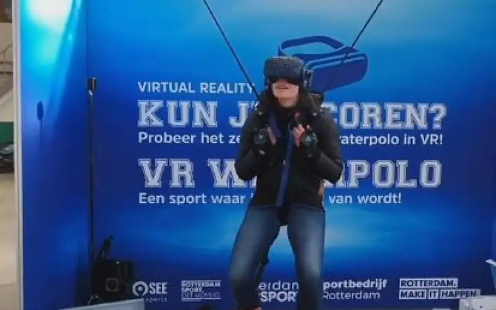 Een deelnemer draagt een VR-bril en houdt controllers vast om waterpolo virtueel te ervaren.