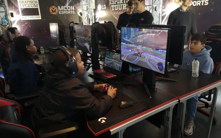 Een groep jongeren speelt een game achter computers in een esports-toernooiomgeving.