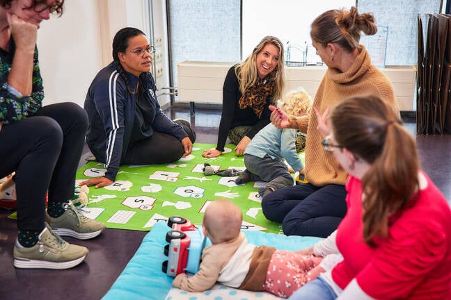 Kinderen met ouders aan het spelen op de grond