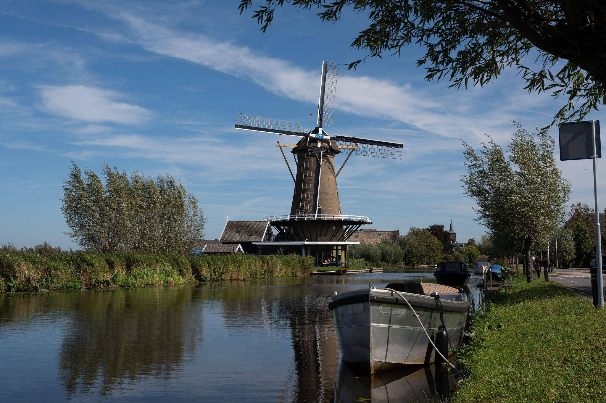 Foto van de rivier bij Bleskensgraaf met op de voorgrond een sloep en op de achtergrond de molen.