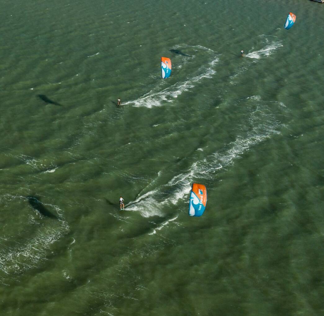 Multiple Van Oord kiters surfing across the sea