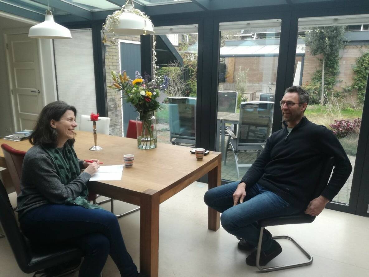 Op de foto zie je hoe redacteur Mariska Brouwer stadshovenier Adriaan Mosterman interviewt aan zijn keukentafel.